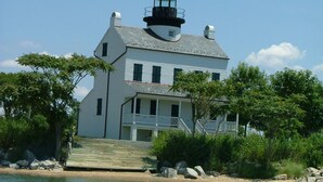 A white building with a lighthouse on top, a balcony, and a staircase leading to the entrance.
