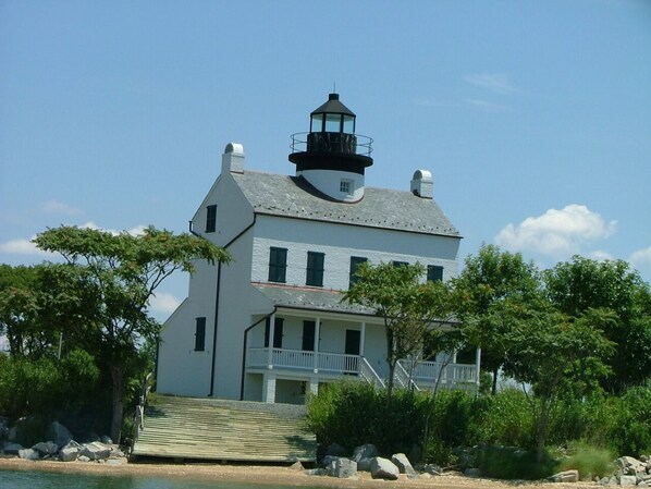 A white building with a lighthouse on top, a balcony, and a staircase leading to the entrance.