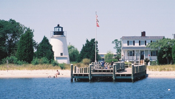 A lighthouse, a pier, and a building by the water.