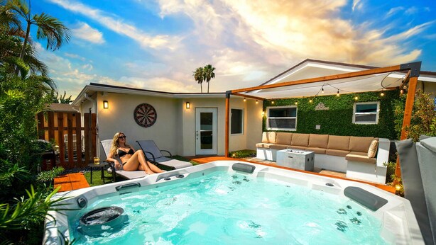 A backyard with a swimming pool, lounge chairs, a hot tub, and a covered patio area. - Modern 6BR Home • Jacuzzi_BBQ, Game Room & Games (Miami)