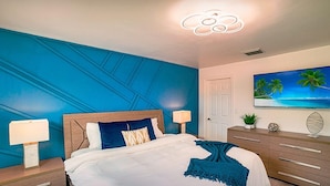 A bedroom with a bed, nightstands, a dresser, a TV, and a ceiling light fixture. - Modern 6BR Home • Jacuzzi_BBQ, Game Room & Games (Miami)