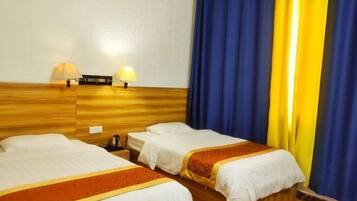 Ett hotellrum med två separata sängar, en sänggavel i trä, två sänglampor och ett litet bord vid sängen med en vattenkokare.