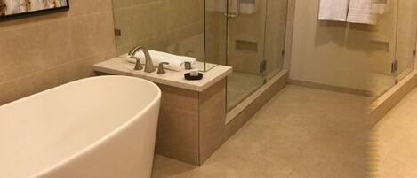 A modern bathroom with a freestanding bathtub, a glass-enclosed shower, and a small vanity with a sink and towel rack.