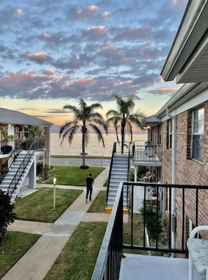 A residential building with a balcony, a staircase, and a view of the beach.
