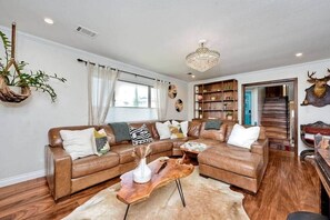 A living room with a sectional sofa, wooden coffee table, and a chandelier.