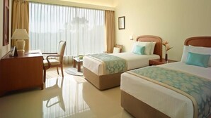 A hotel room with two beds, a desk, a chair, and a large window with curtains. - Ginger Gondia, Balaghat Road (Gondia)