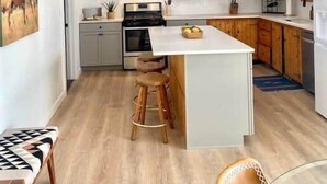 Een moderne keuken met houten kastjes, een centraal eiland, barstoelen en hanglampen.