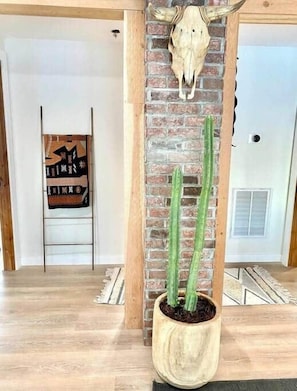 A room with a brick wall, a potted plant, and a ladder leaning against the wall.