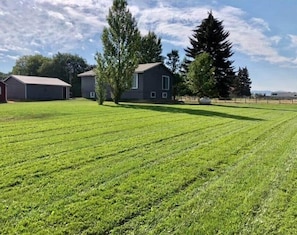 A grassy field with two buildings, one with a sloped roof and another with a flat roof.