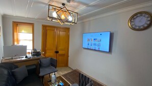 A living room with a sofa, a coffee table, a TV mounted on the wall, and a ceiling light fixture. - New Cherry Hotel (Istanbul)