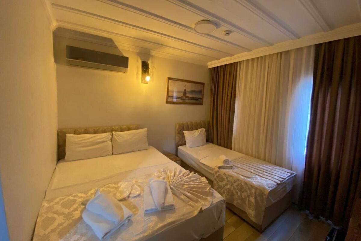 A hotel room with two beds, a painting on the wall, and a window with curtains.