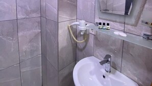 A modern bathroom with a white sink, a handheld showerhead, and a mirror above the sink. - New Cherry Hotel (Istanbul)