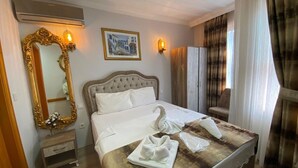 A hotel room with a bed, a large ornate mirror, a wall-mounted light, and a painting. - New Cherry Hotel (Istanbul)