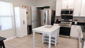 Une cuisine moderne avec des armoires blanches, des appareils en acier inoxydable et un plancher en bois.