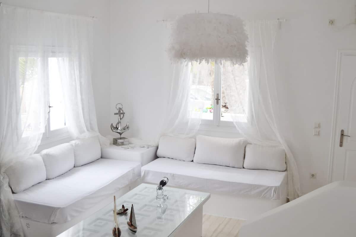 A white room with a sofa, a glass coffee table, and a decorative anchor.