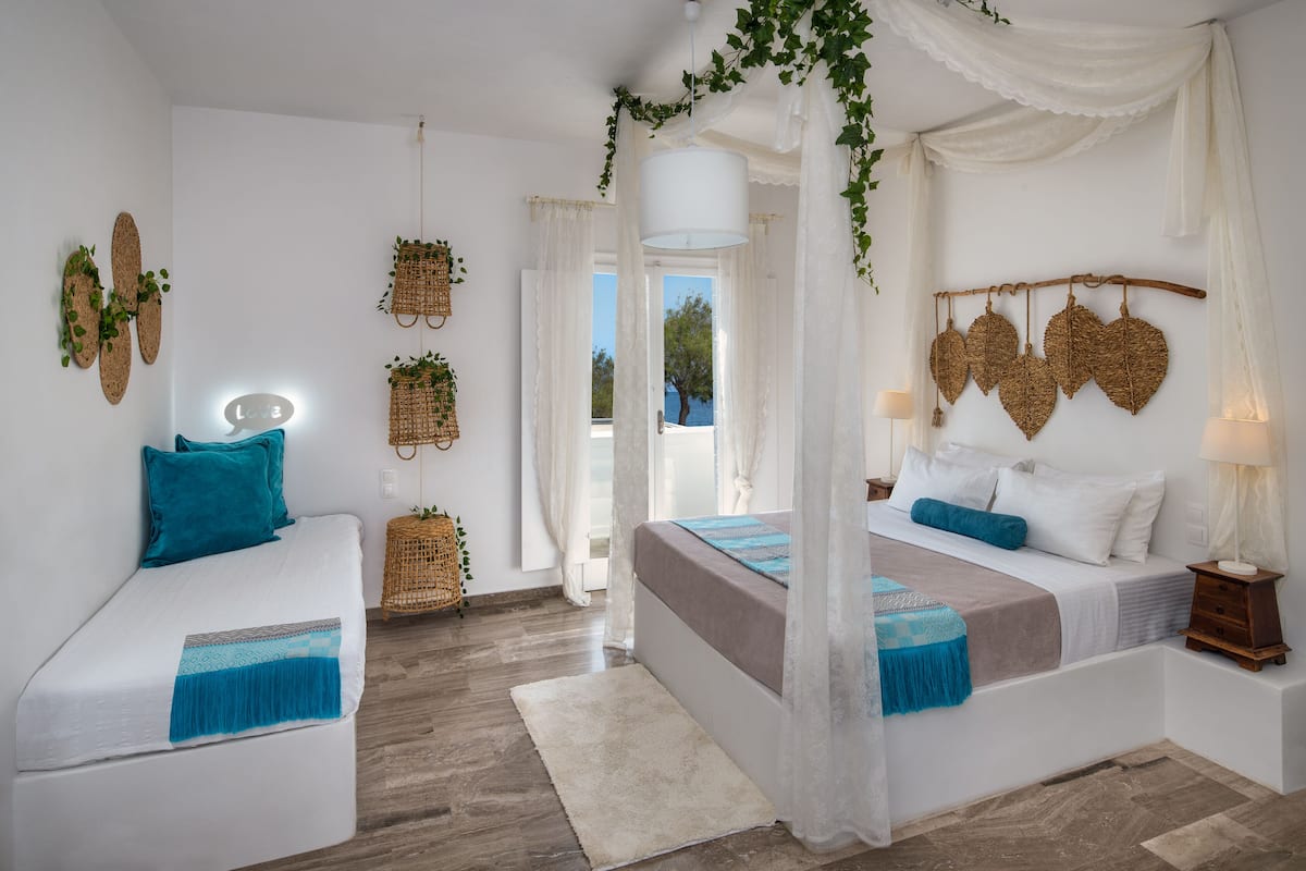 A bedroom with a bed, bedside tables, a bedside lamp, a hanging plant, and a view of the outdoors.
