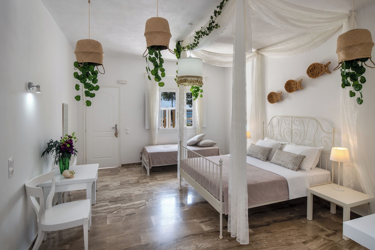 A bedroom with a bed, bedside tables, and hanging baskets with green plants.