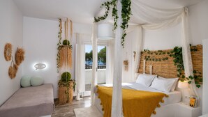 A modern bedroom with a bed, bedside table, and a bench. - Sol Mare Salis (Santorini)