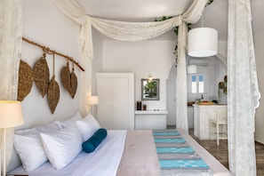 Un dormitorio con cama, lámpara de noche y vista a la cocina.