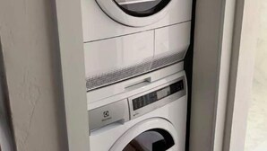Una lavadora y secadora apiladas, con un panel de control y una pequeña ventana.