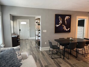 A modern living room with a dining area, grey walls, and a wooden floor.