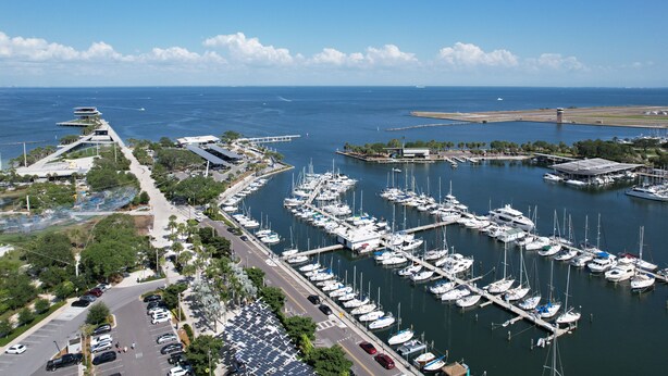A marina with numerous boats docked, a parking lot, and a clear view of the ocean.