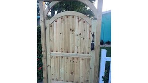 Una reja de madera con un candado y una cerradura, dentro de una estructura de madera con parte superior curva.