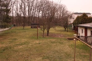 Ein Rasen mit einem kleinen Schuppen, einem Baum und einem Zaun.