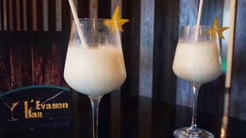 Two glasses of a creamy beverage with star-shaped garnishes on a bar counter, with a 'L'Evasion Bar' sign in the background.