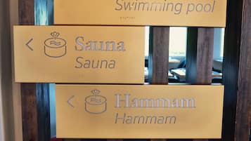 Un cartel direccional con flechas que indican los servicios: piscina, sauna y hammam.