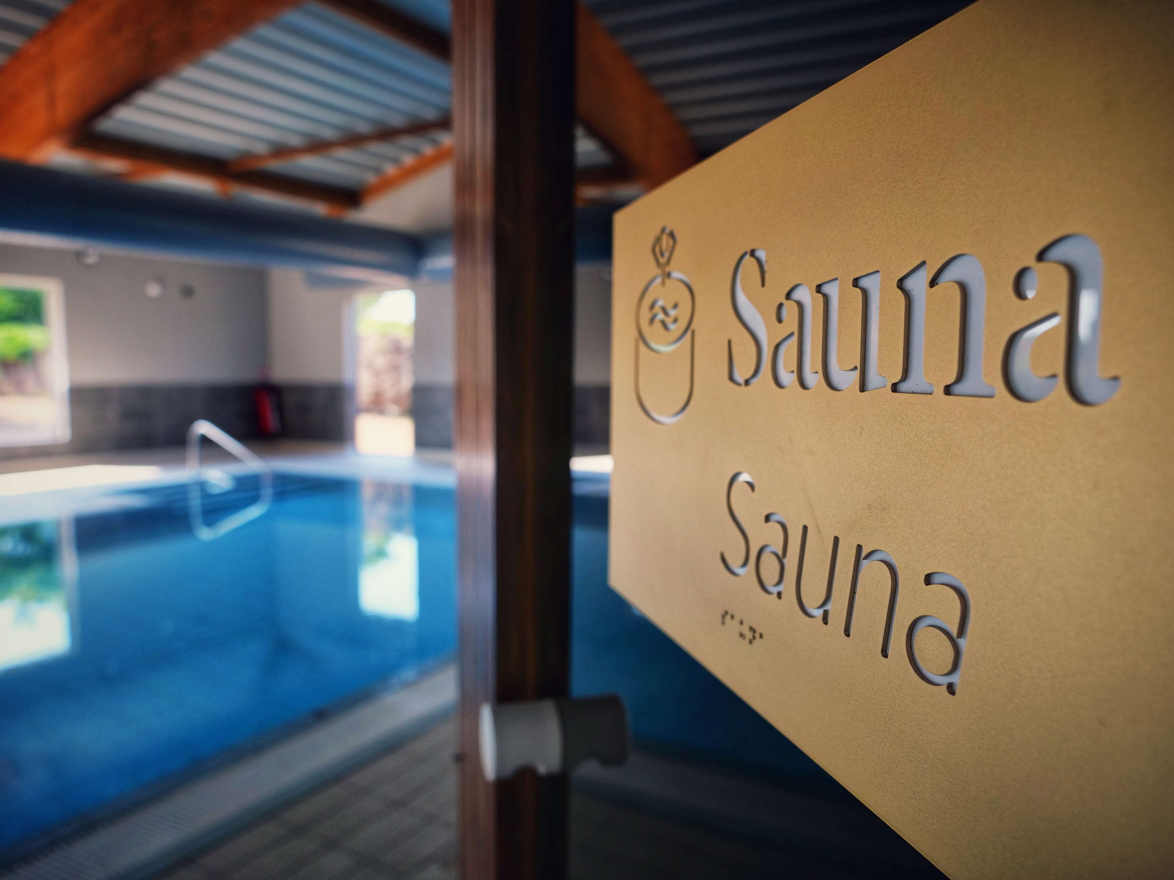 A sign for a sauna with a pool in the background.