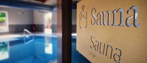 A sign for a sauna with a pool in the background.