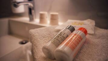 A bathroom with a white sink, two bottles of lotion, and a towel on a white bath mat.