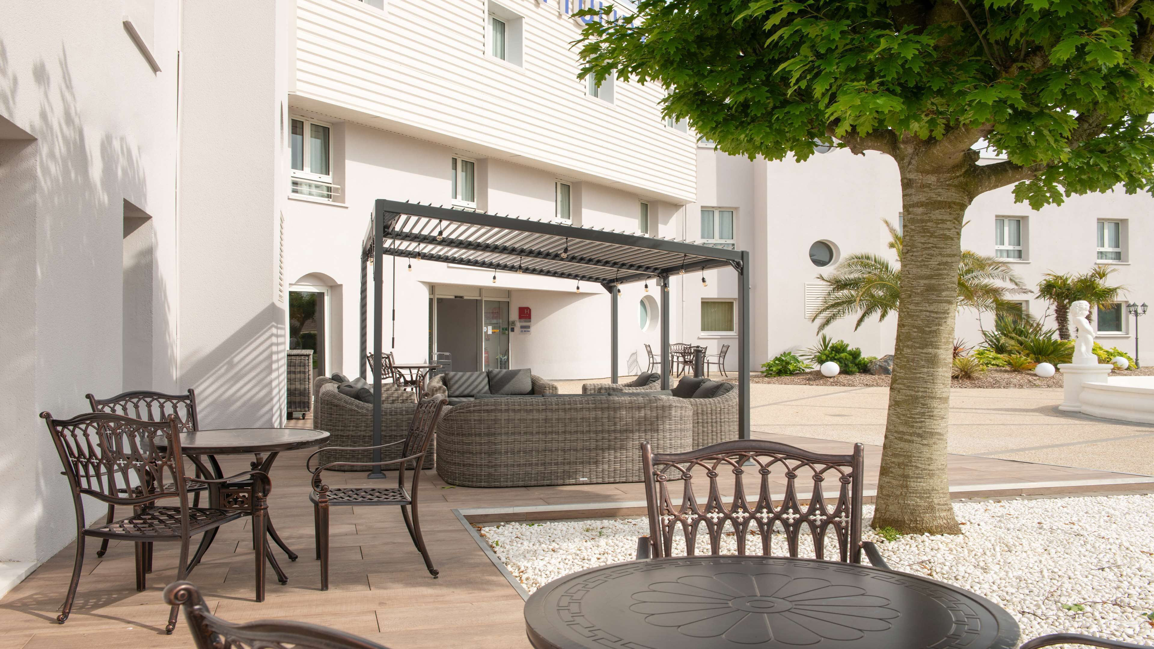 An outdoor seating area with wicker furniture, a pergola, and a palm tree.