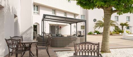 An outdoor seating area with wicker furniture, a pergola, and a palm tree.