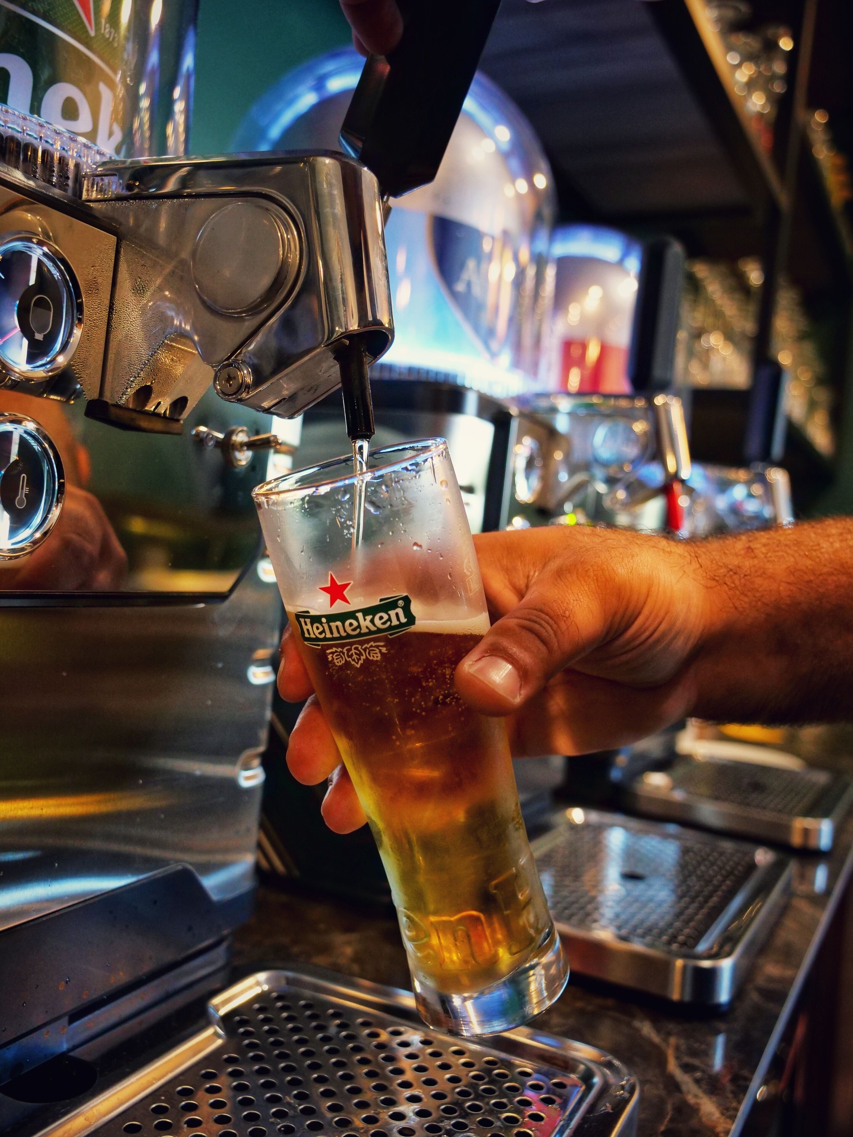 Una mano sosteniendo una cerveza Heineken mientras se sirve desde un grifo.