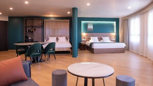 Une chambre d’hôtel moderne avec un grand lit, un coin repas avec des chaises, une petite table et un canapé.
