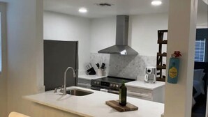 Een moderne keuken met een centraal eiland, een inbouwoven en een roestvrijstalen afzuigkap.
