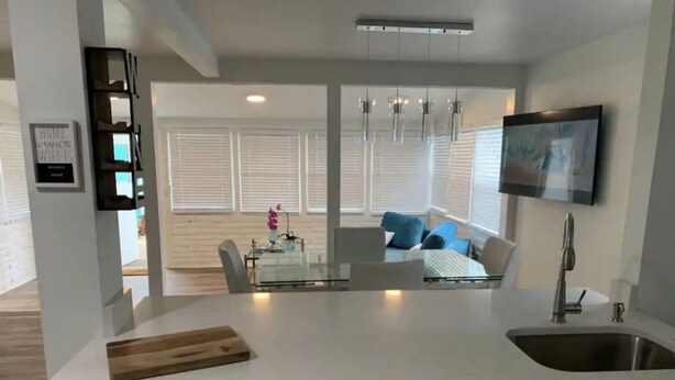 Een moderne keuken met witte kastjes, een centraal eiland met een snijplank en een inbouwspoelbak.