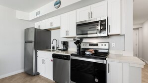 Une cuisine moderne avec des armoires blanches, des appareils en acier inoxydable et une horloge au mur.