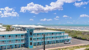 Un motel à plusieurs étages doté de balcons donnant sur une plage.