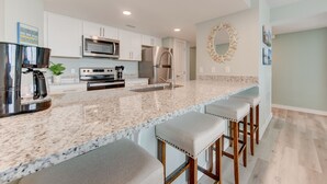 A modern kitchen with white cabinets, stainless steel appliances, and a granite countertop. - Sandcastle Condominiums Unit 523 (Port Aransas)