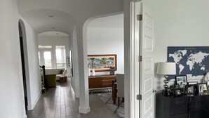 A spacious hallway with a wooden floor, a dining area with a wooden table and chairs, and a large world map on the wall. - Modern Spacious Living (Austin)