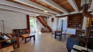 Un vaste espace de vie comprenant un escalier en bois, une table à manger avec des chaises et un coin cuisine équipé d’une cuisinière.