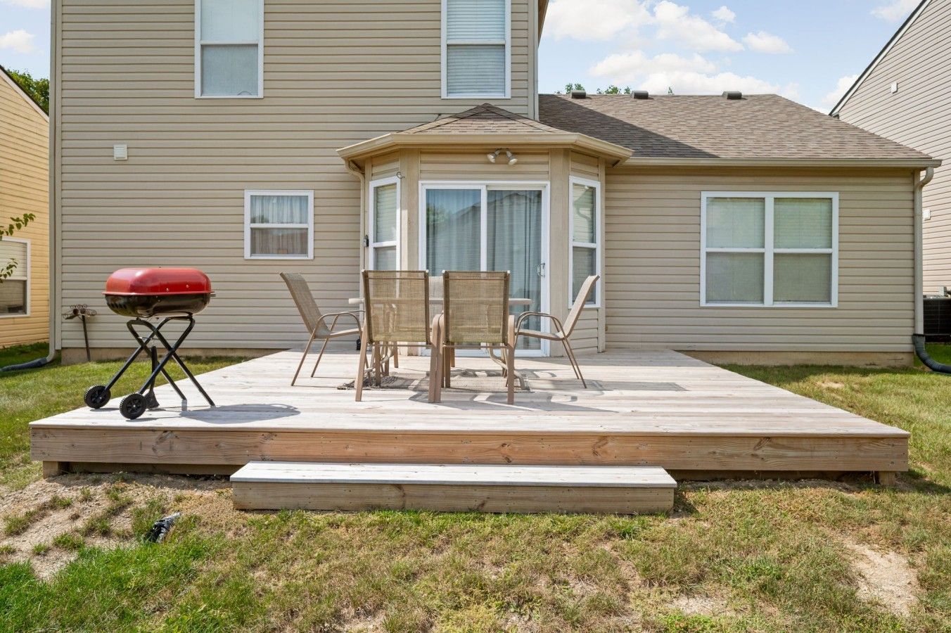 Ein Garten mit einer Holzterrasse, einem Grill und Gartenmöbeln.