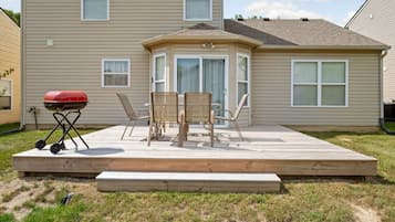 A backyard with a wooden deck, a barbecue grill, and outdoor furniture.