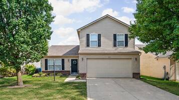 A two-story house with a garage, a front yard, and a driveway.