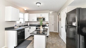 A compact kitchen with white cabinets, a black refrigerator, and a central island.