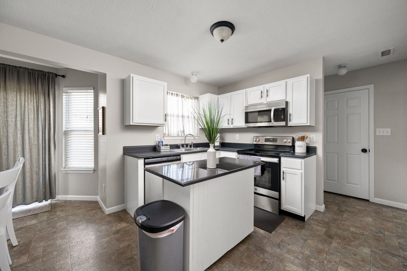 A modern kitchen with white cabinets, stainless steel appliances, and a central island.