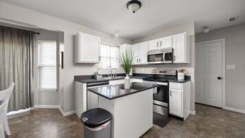 A modern kitchen with white cabinets, stainless steel appliances, and a central island.